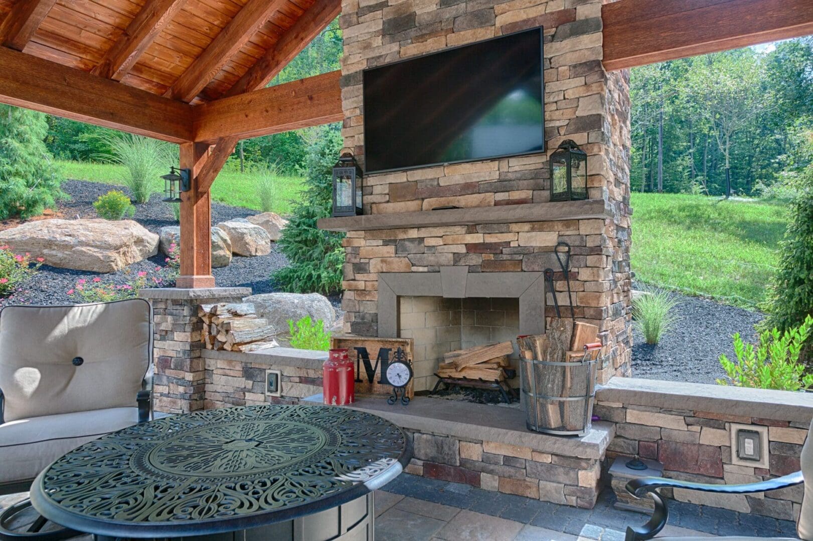 A covered patio with a stone fireplace and tv, providing cozy outdoor services.