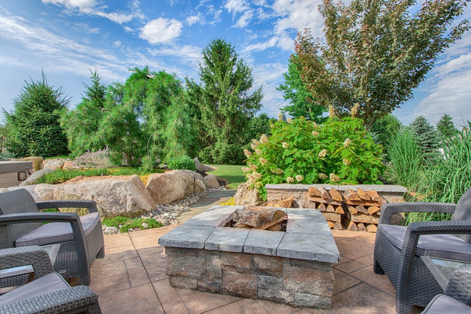 A custom backyard with wicker furniture and a fire pit.