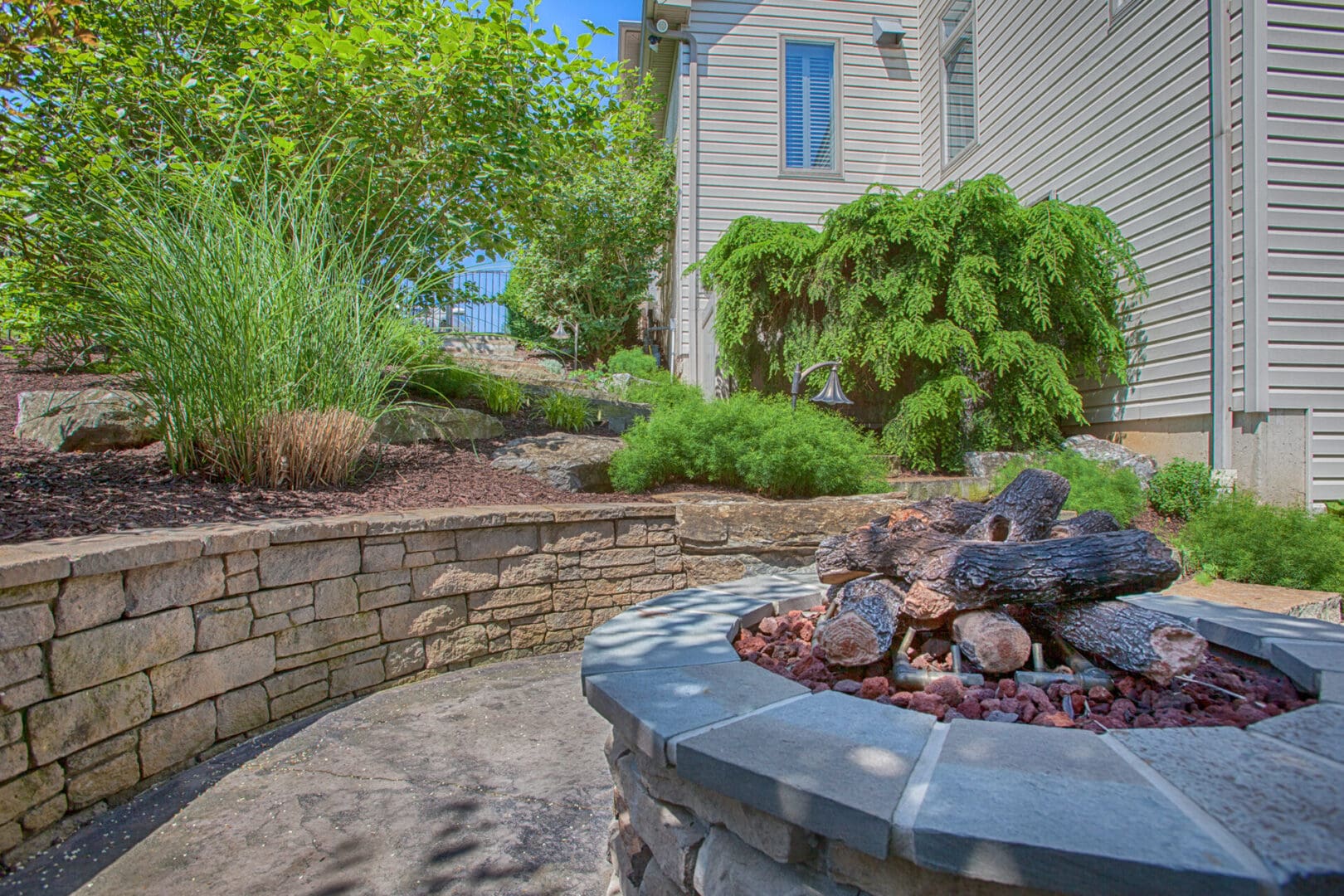 A custom stone fire pit in front of a house.