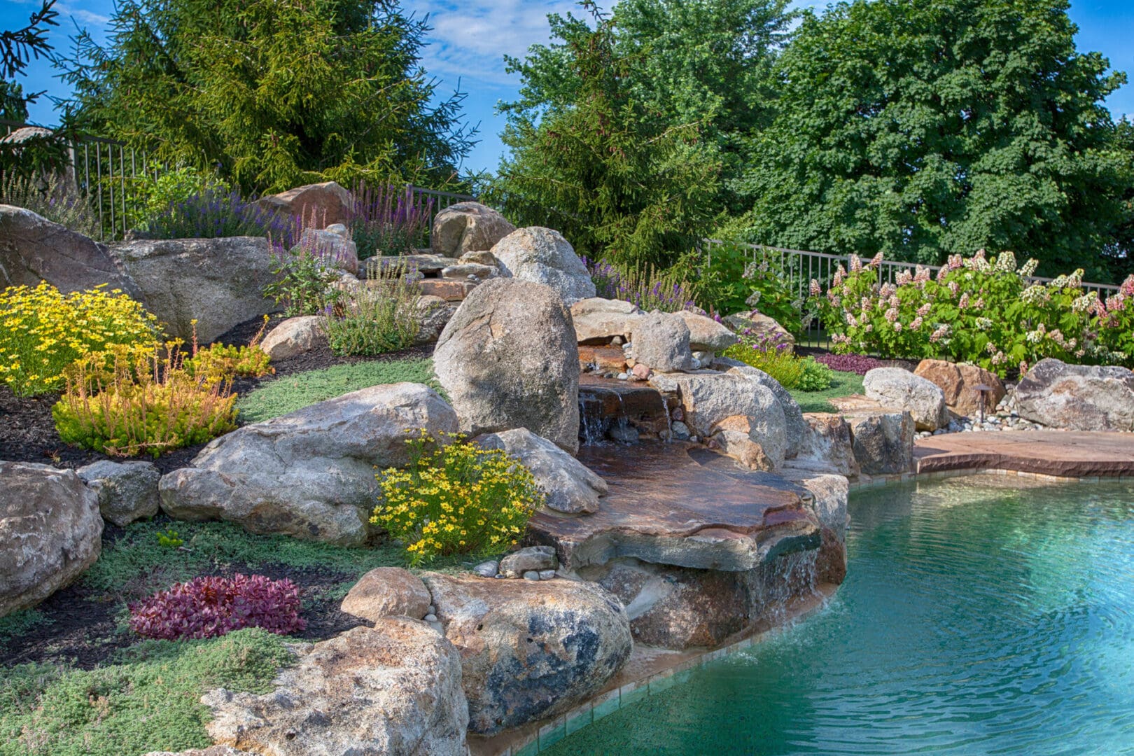 A swimming pool with water features such as rocks and a waterfall.