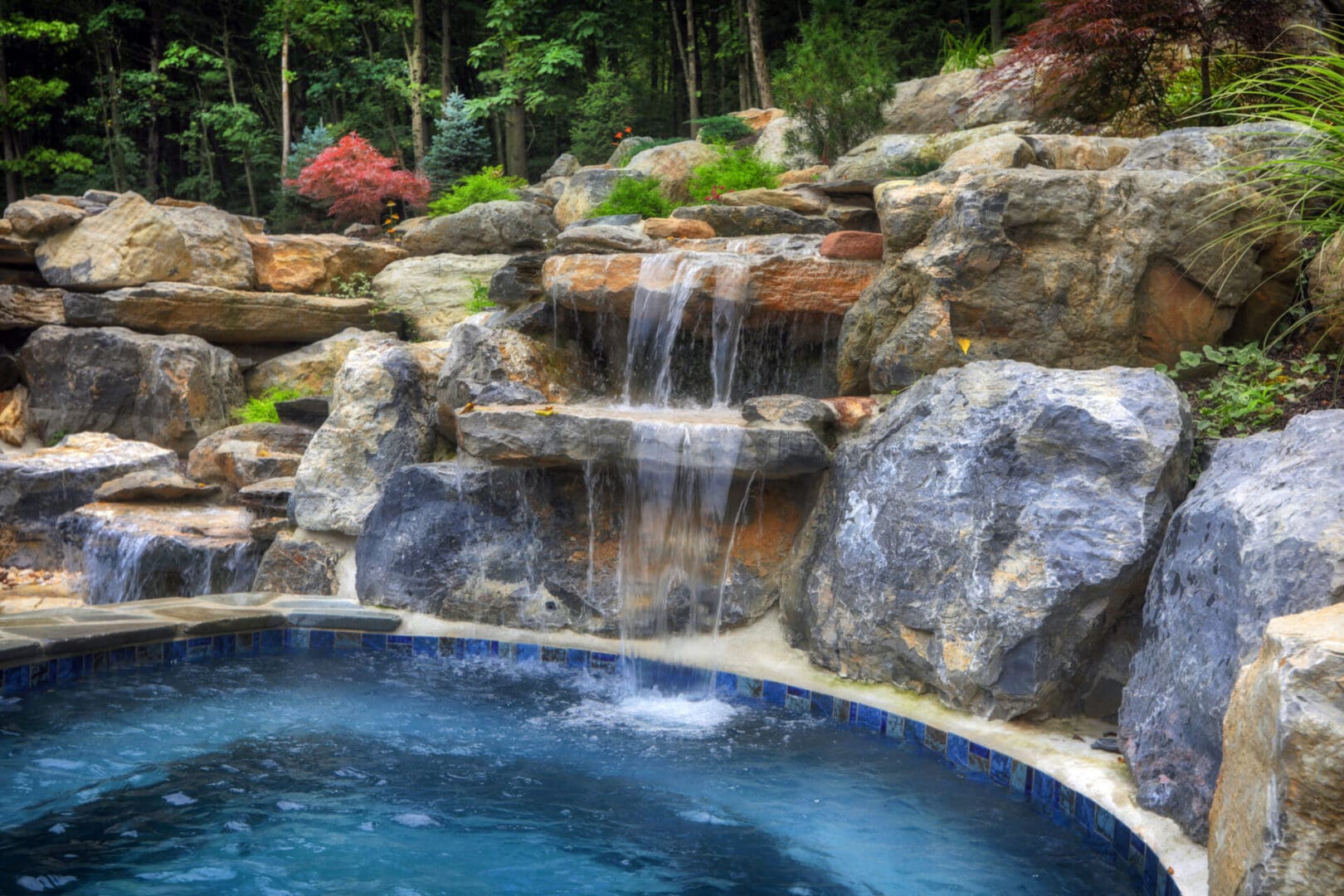 A pool with a waterfall, featuring water elements and surrounded by rocks.
