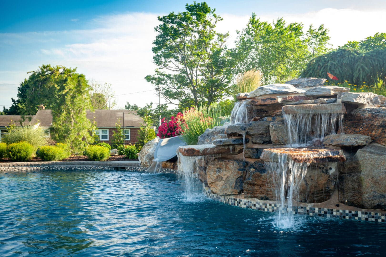 A swimming pool with a mesmerizing waterfall in the middle, showcasing stunning water features.