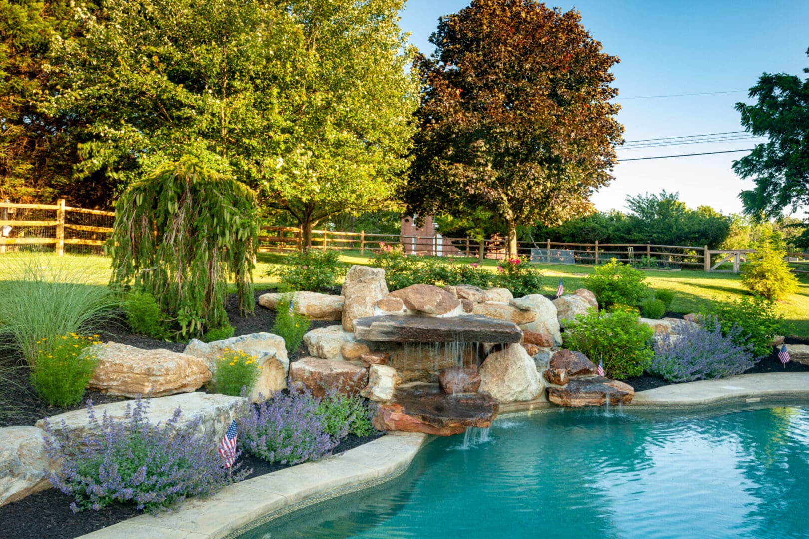 A swimming pool with water features and landscaping including a waterfall.