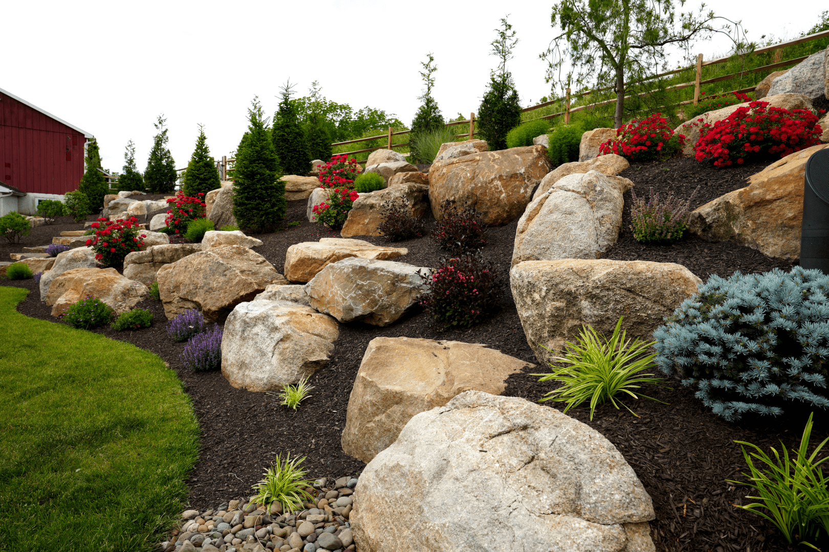 A boulder rock garden with flowers and shrubs.