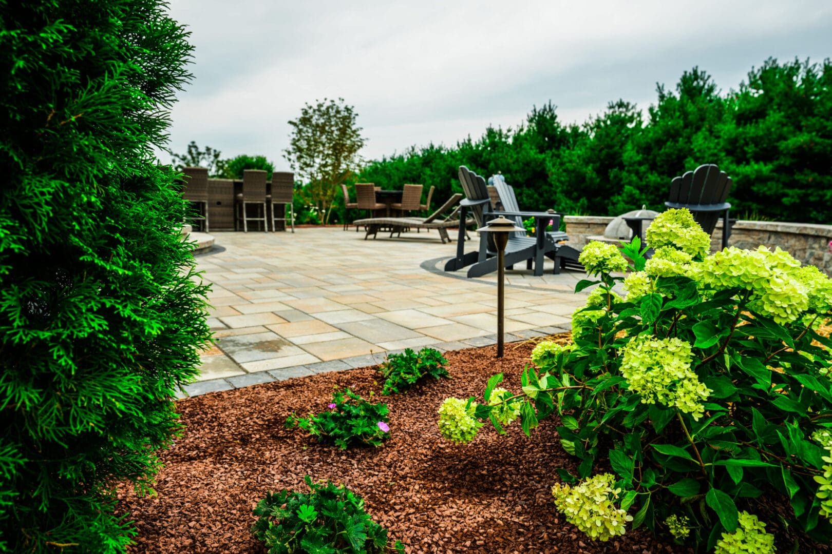 A backyard with professionally crafted landscaping that includes a fire pit.