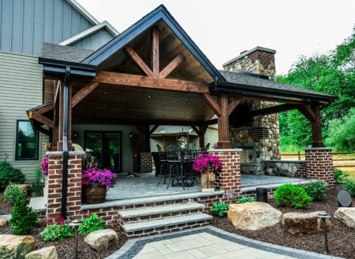 A covered patio with a fireplace and stone walkway, offering services.