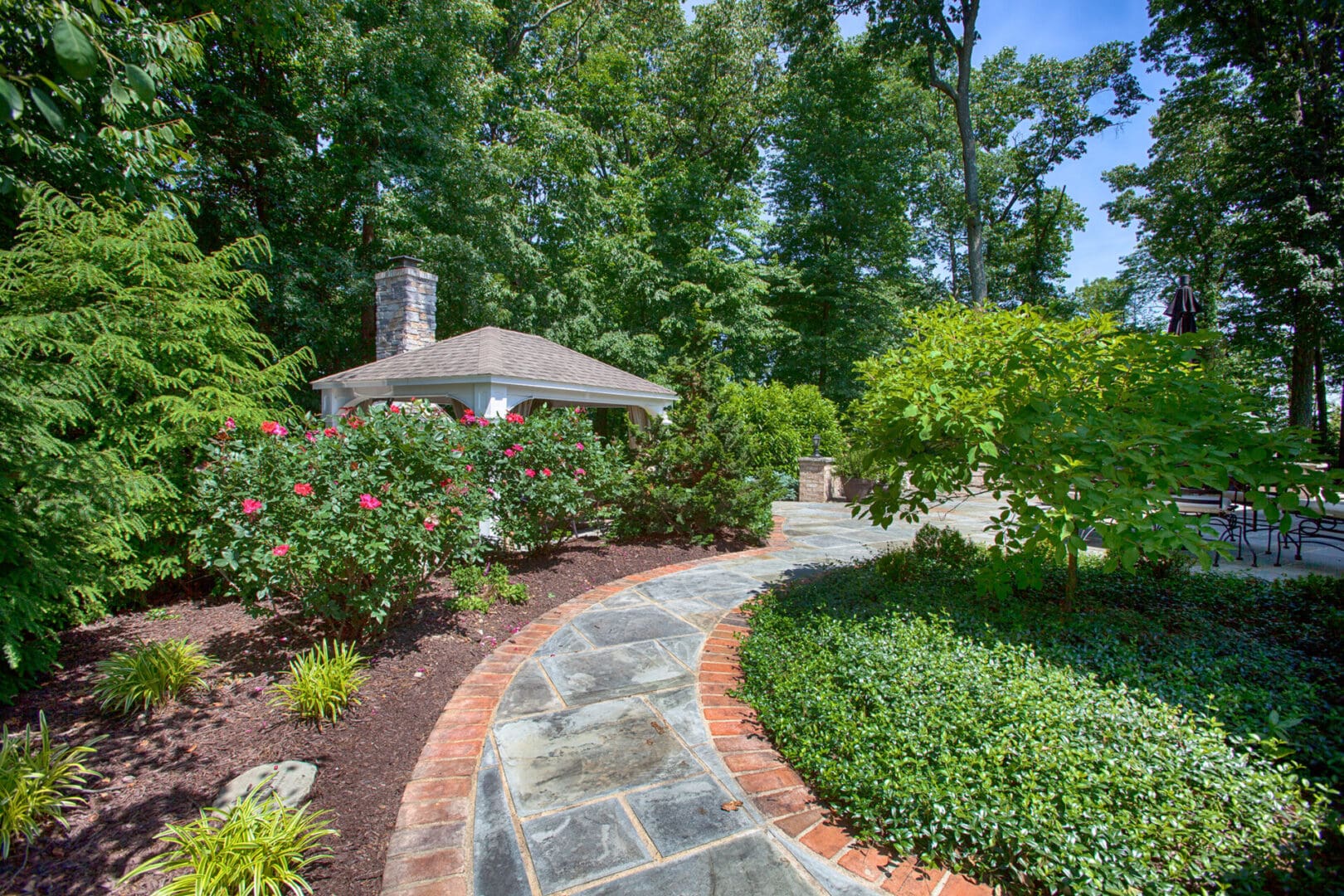 A stone walkway leads to a gazebo in a garden designed by Planting Professionals.