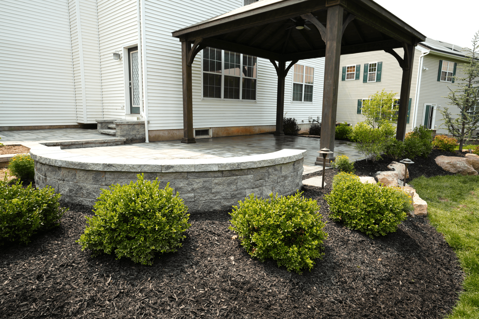 A gazebo in front of a house, designed and constructed by Planting Professionals.