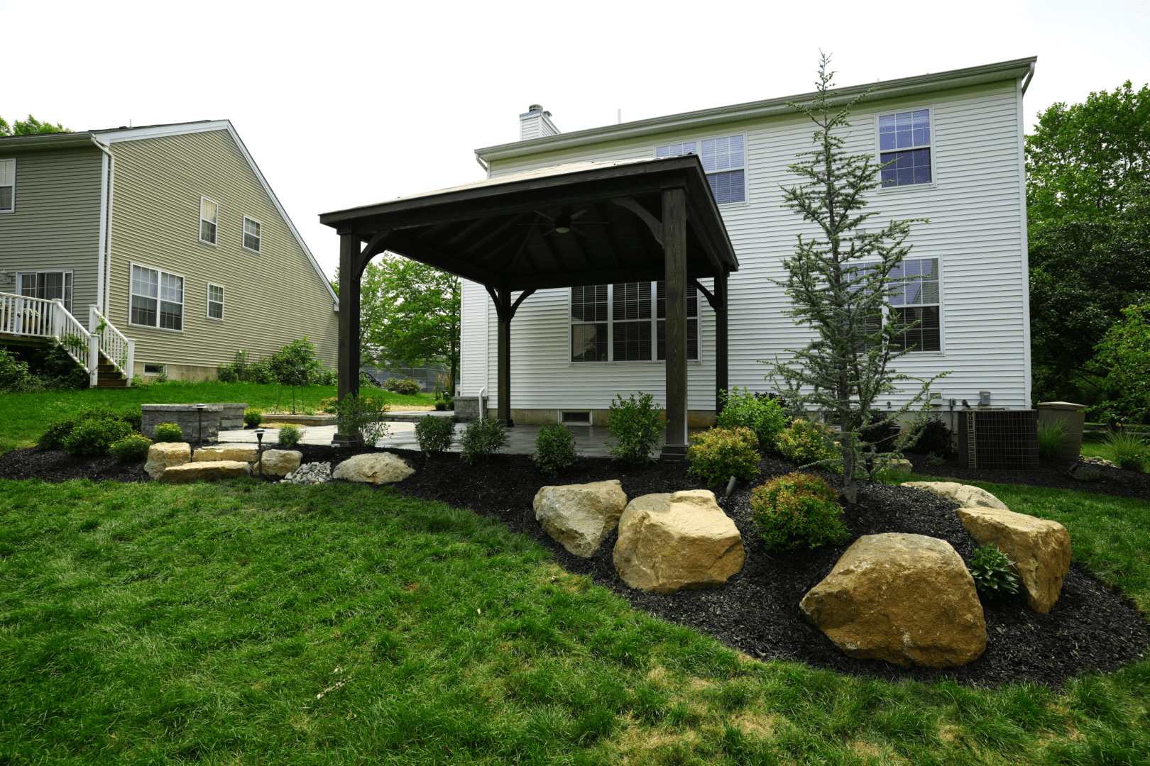 A backyard with a rock garden and gazebo, designed and maintained by experienced Planting Professionals.