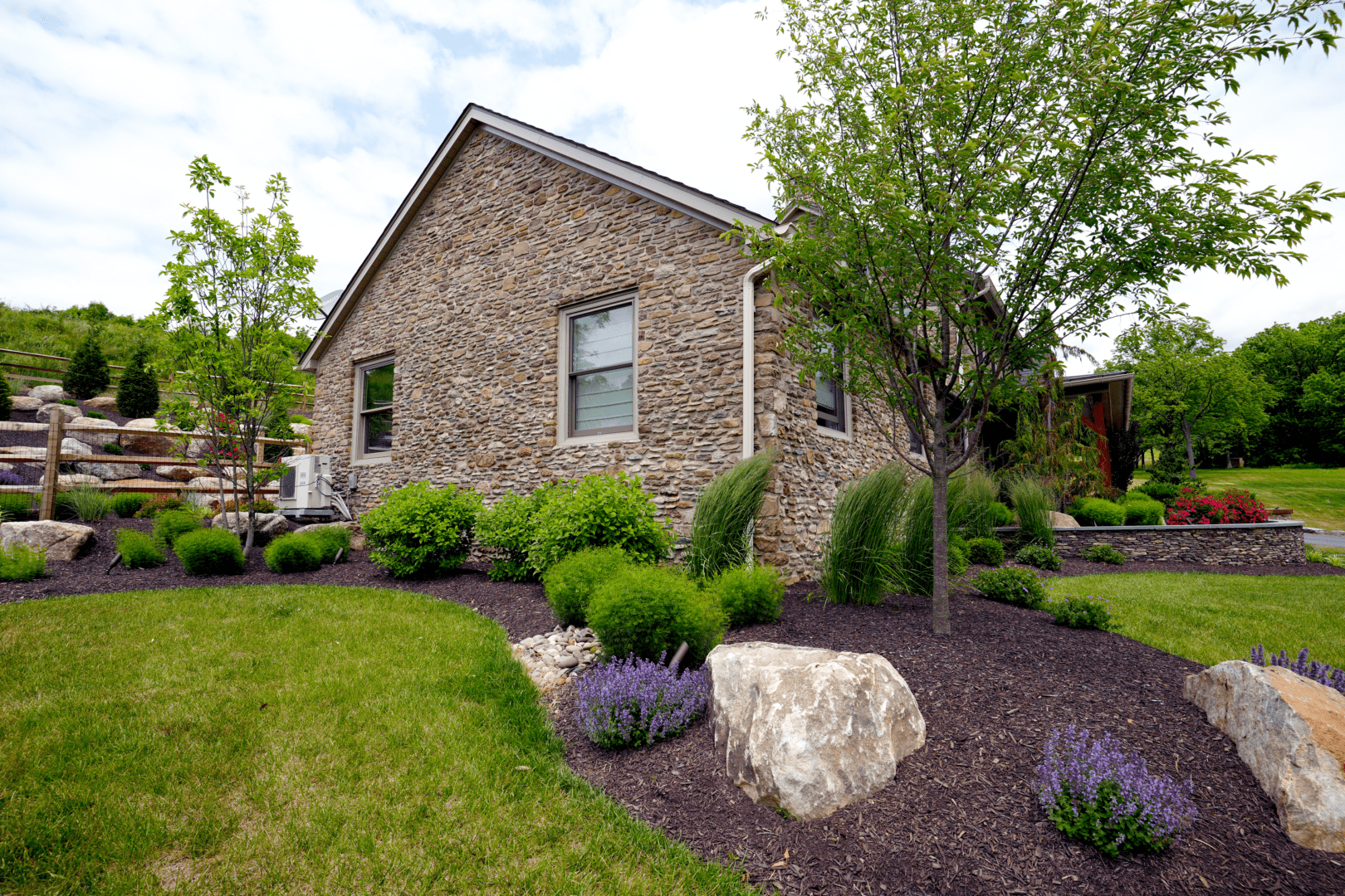 A stone house in a yard expertly landscaped by Planting Professionals.