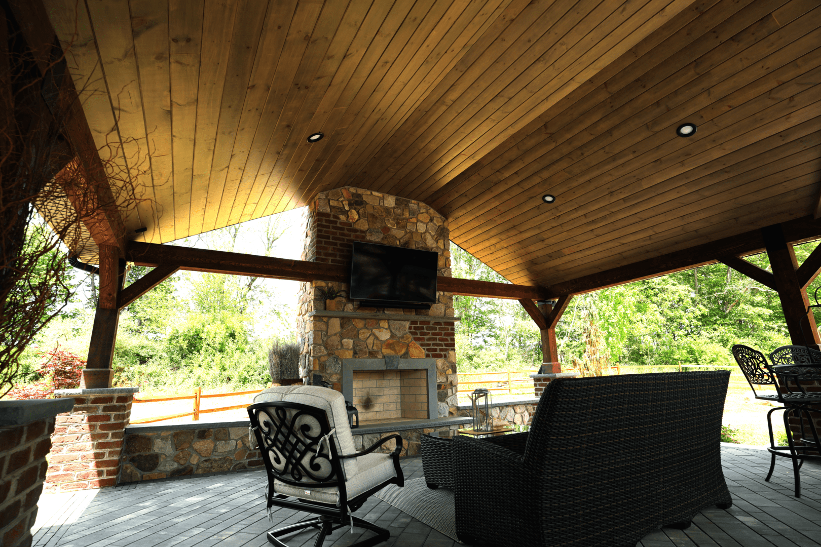A patio featuring custom structures such as a fireplace and a TV.