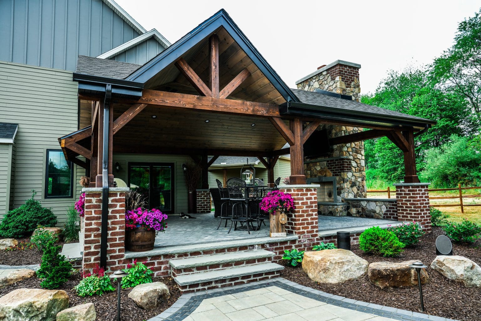 A home with a covered patio and stone walkway showcasing an exquisite landscape design.