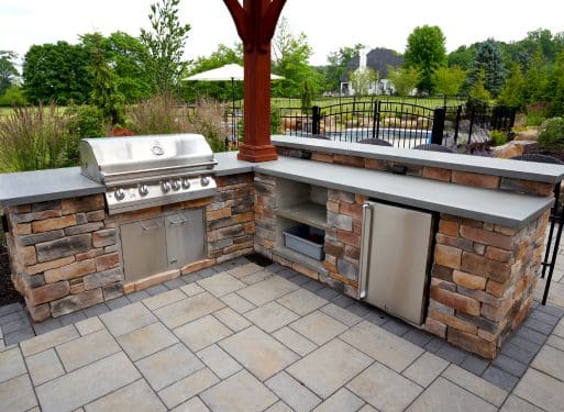 An outdoor kitchen with grill and sink services.
