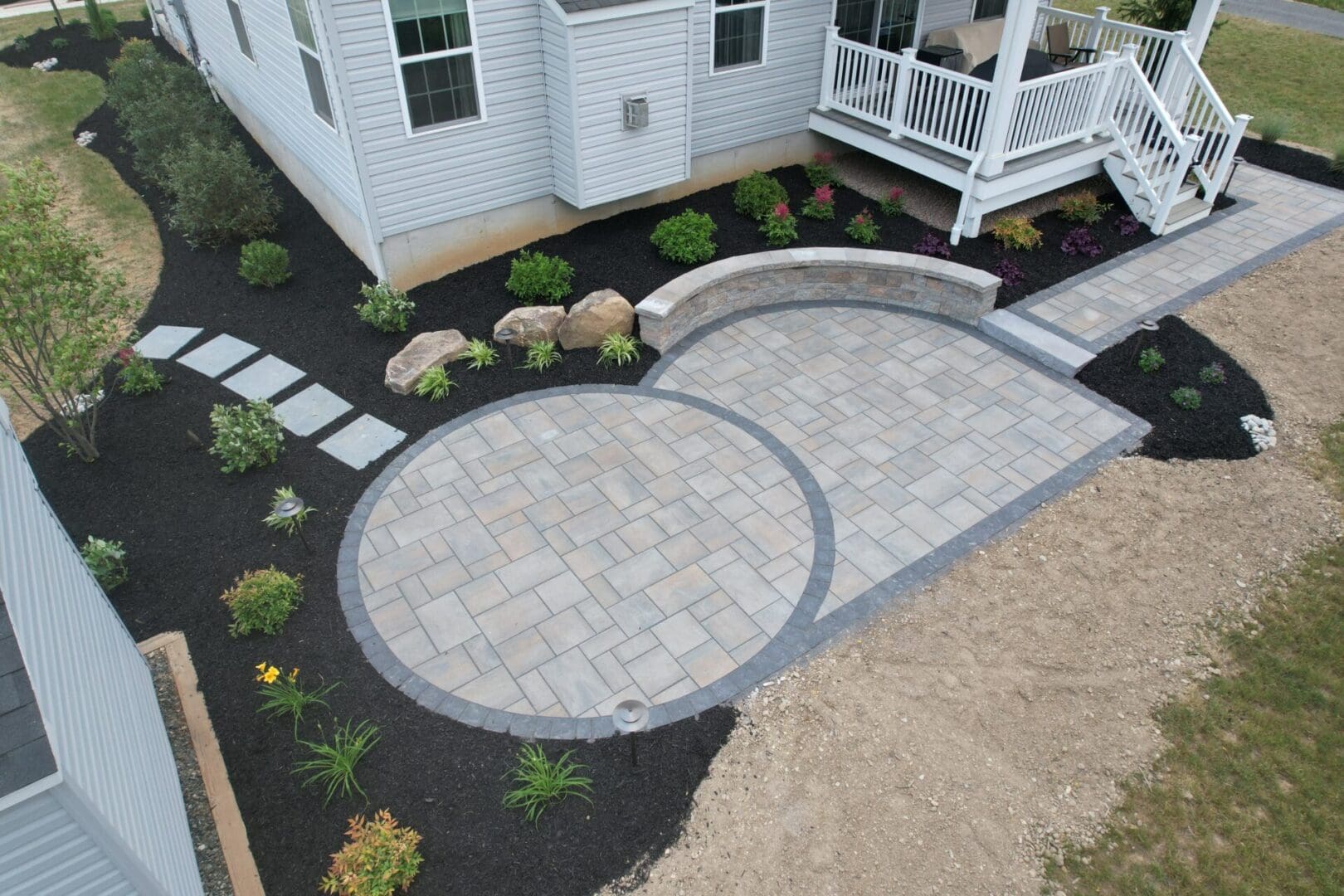 An aerial view of a backyard showcasing a beautifully designed circular patio, highlighting the impeccable hardscape design.