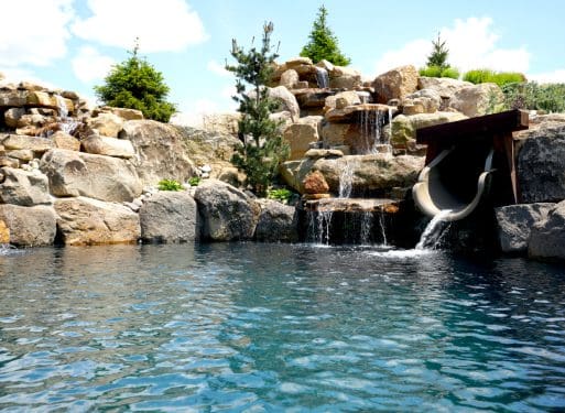 A swimming pool with a waterfall, rocks, and additional services.