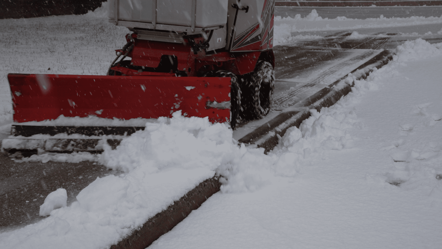 A commercial snow plow is being used to clear snow from a street as part of the snow and ice management process.