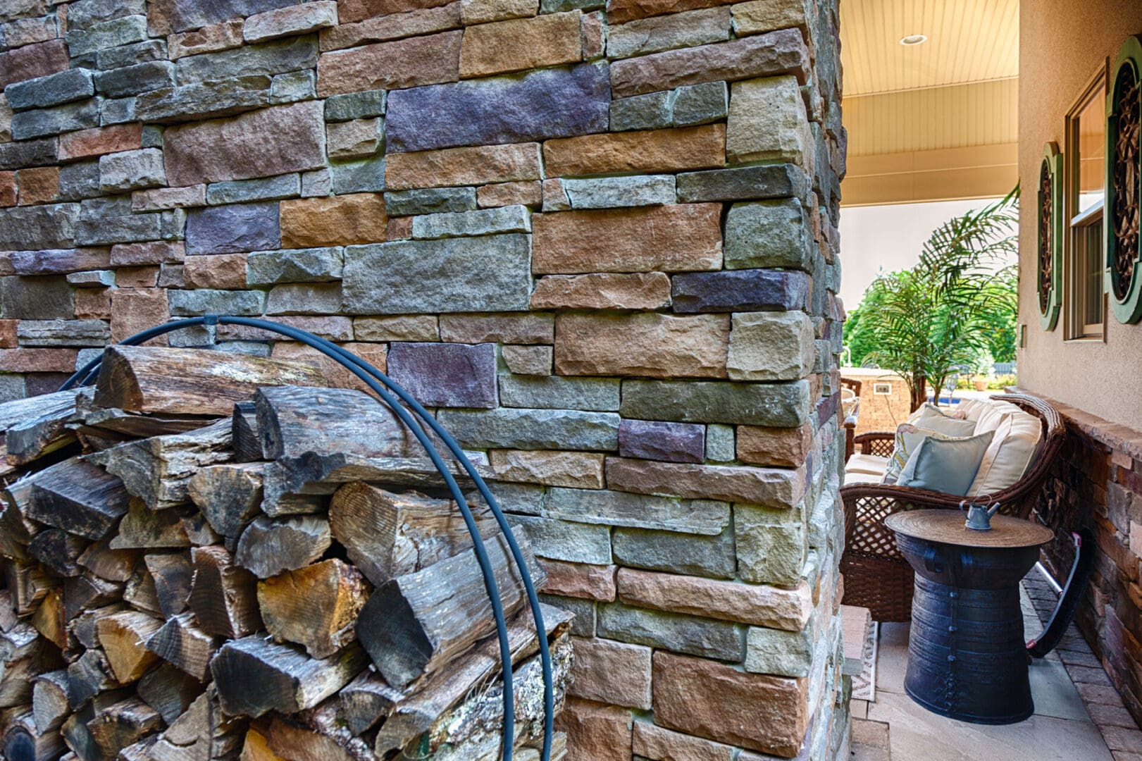 A stone wall showcasing a custom fire pit surrounded by neatly stacked firewood.