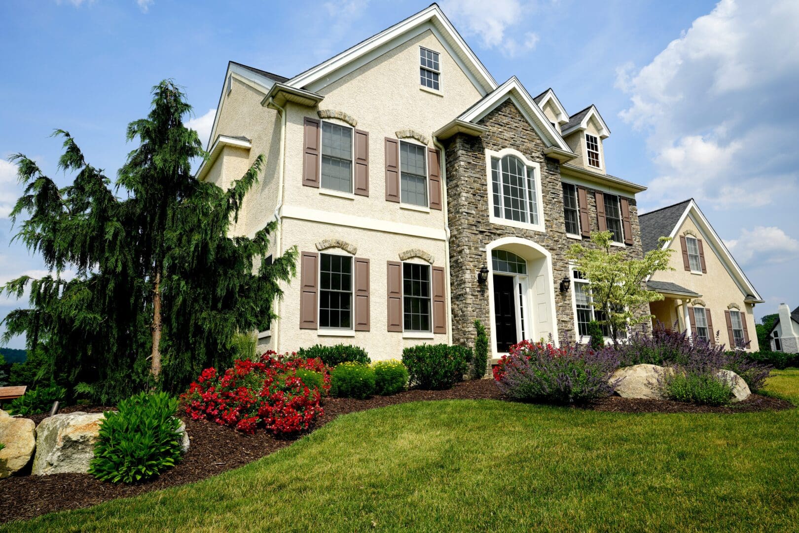 A house with expertly maintained landscaping and bushes in front of it, skillfully designed by Planting Professionals.