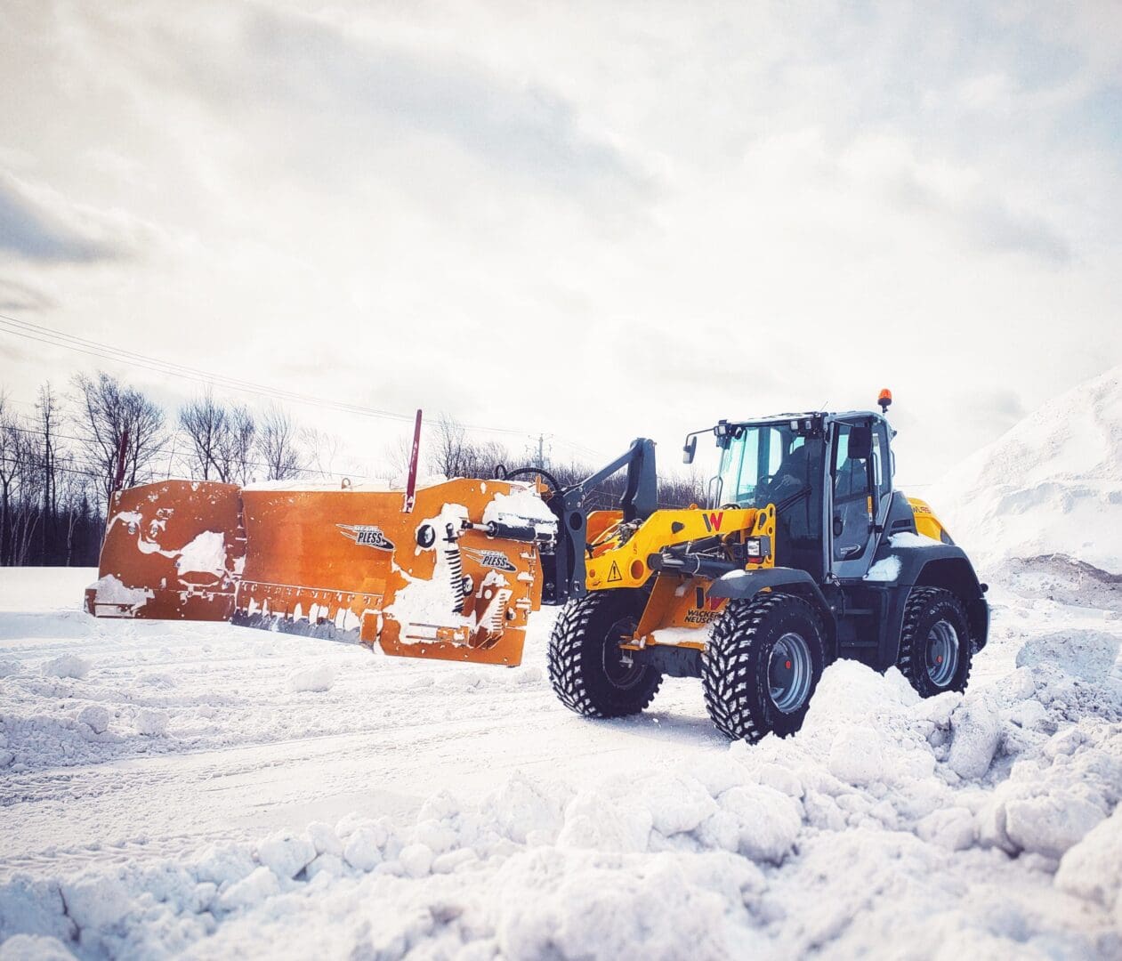 A snow plow and tractor in the snow.