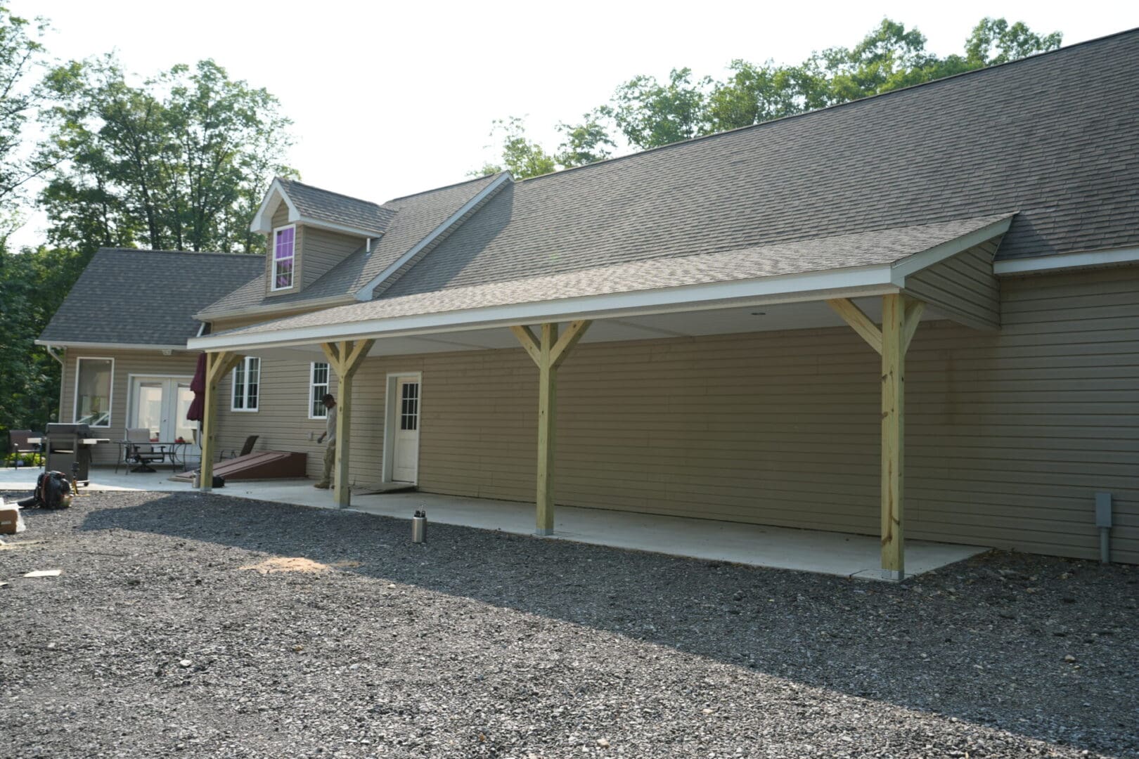 A custom home with a covered porch and a gravel driveway.