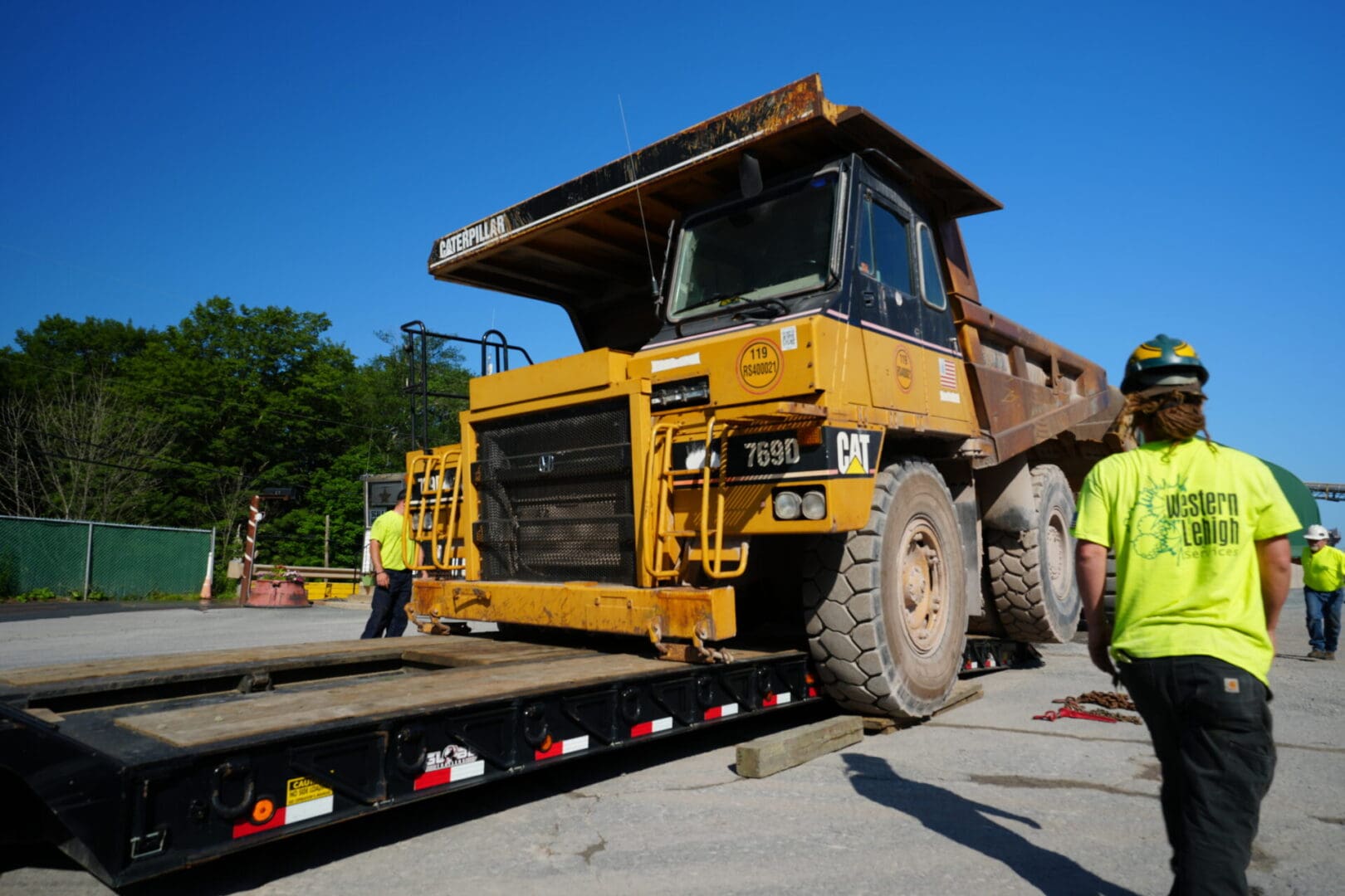 A yellow dump truck on a flatbed equipped with Metal Pless.