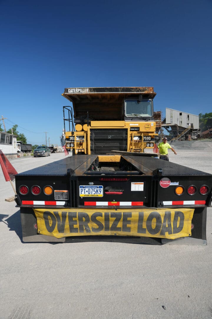 A metal pless oversize load truck is parked in a parking lot.