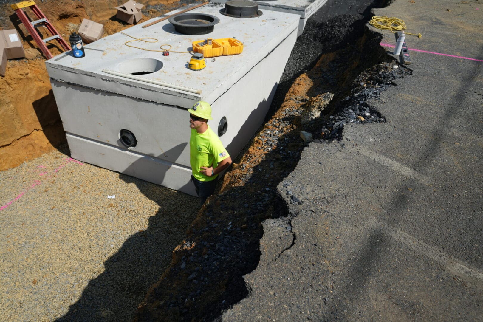 A man is standing at a construction site next to a hole in the road.