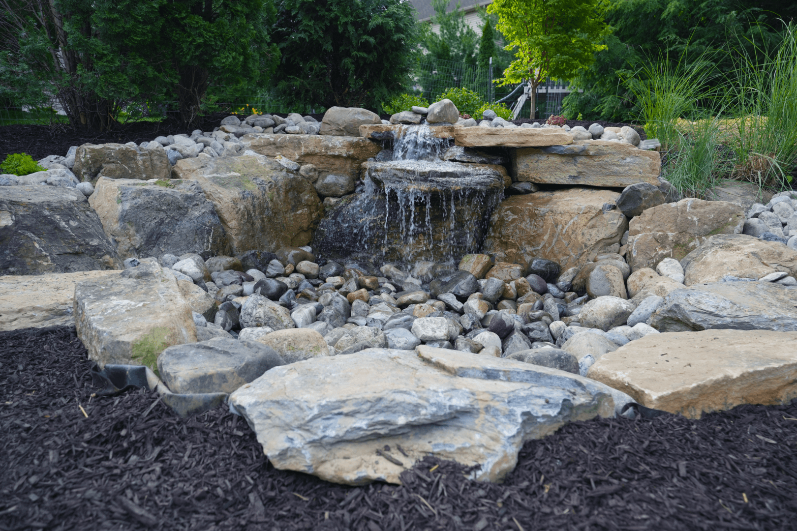 A water feature in a backyard with rocks and gravel.