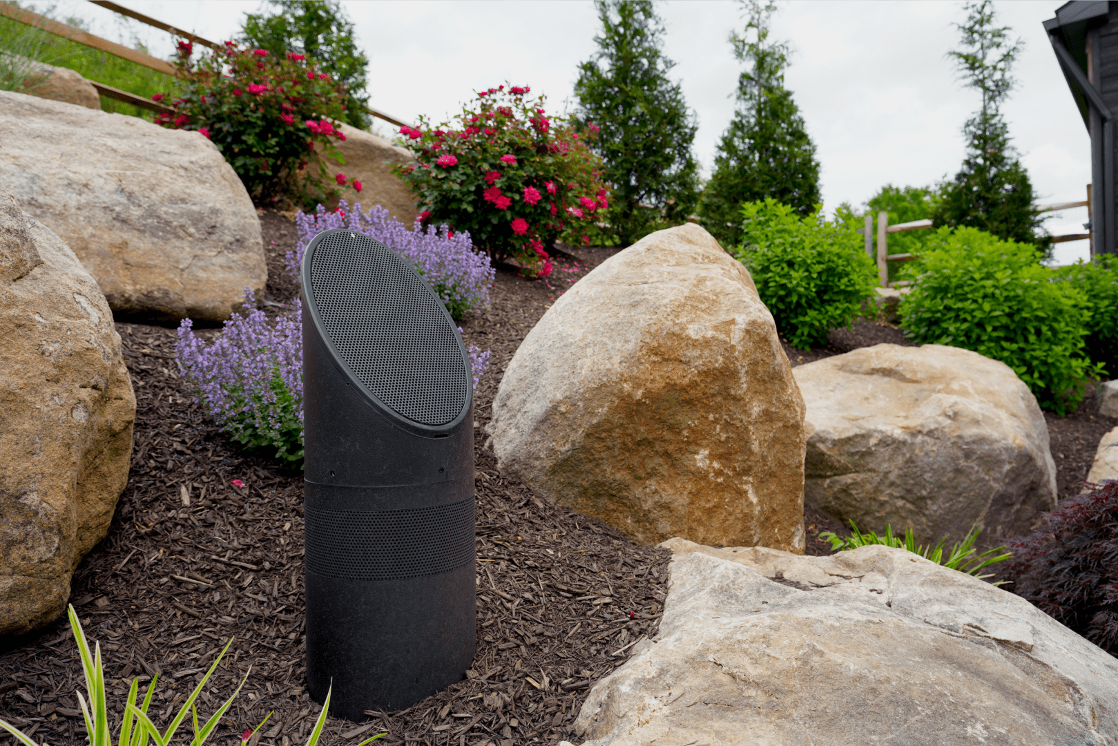 A large rock in the middle of a garden, enhanced with subtle outdoor lighting.