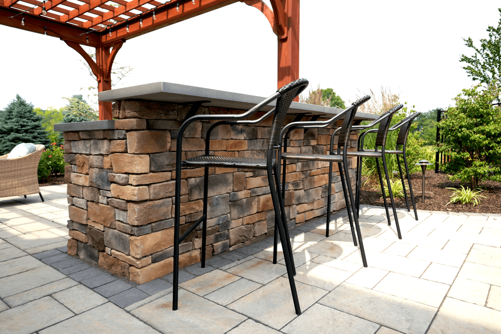 A custom stone patio with a bar and stools for outdoor entertainment.