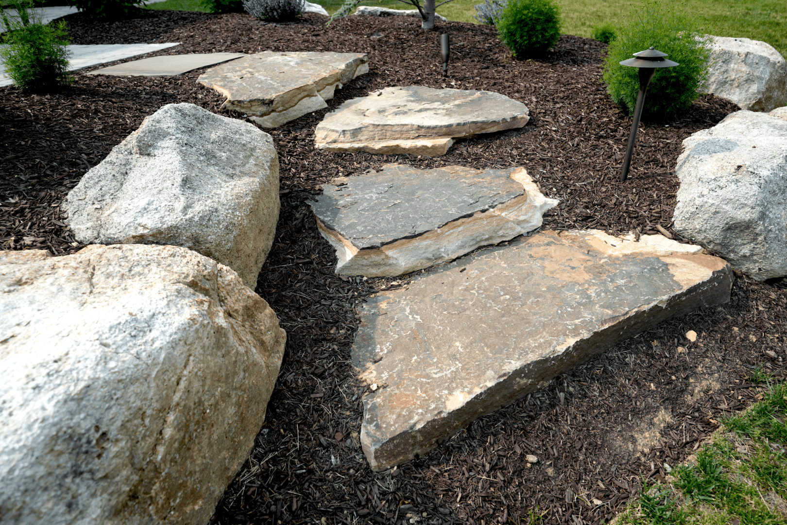 A stone path with boulders in a garden.