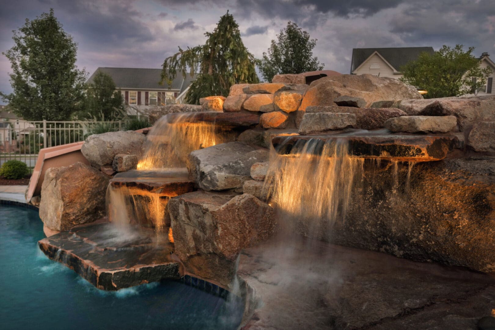 A pool with a stunning waterfall in the middle, enhanced by mesmerizing outdoor lighting and audio.