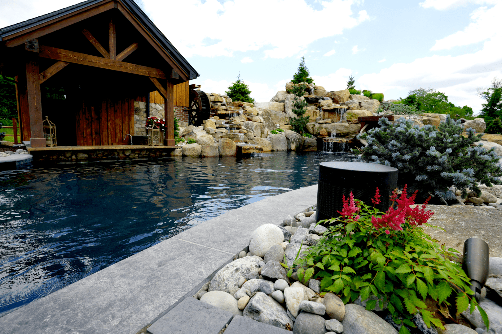 A swimming pool in a backyard, enhanced with outdoor lighting and audio features.