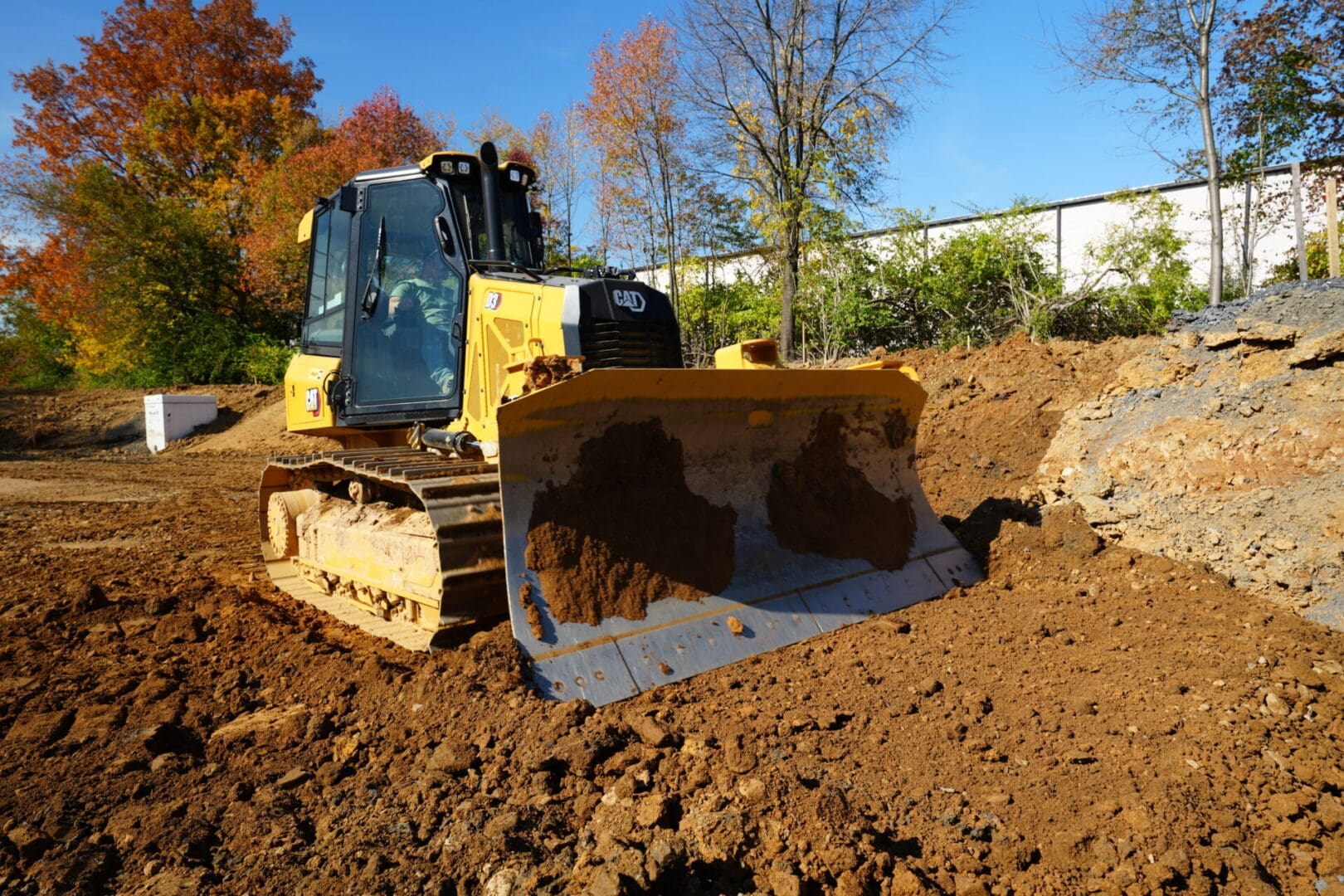 A yellow bulldozer performing site work in a dirt field.