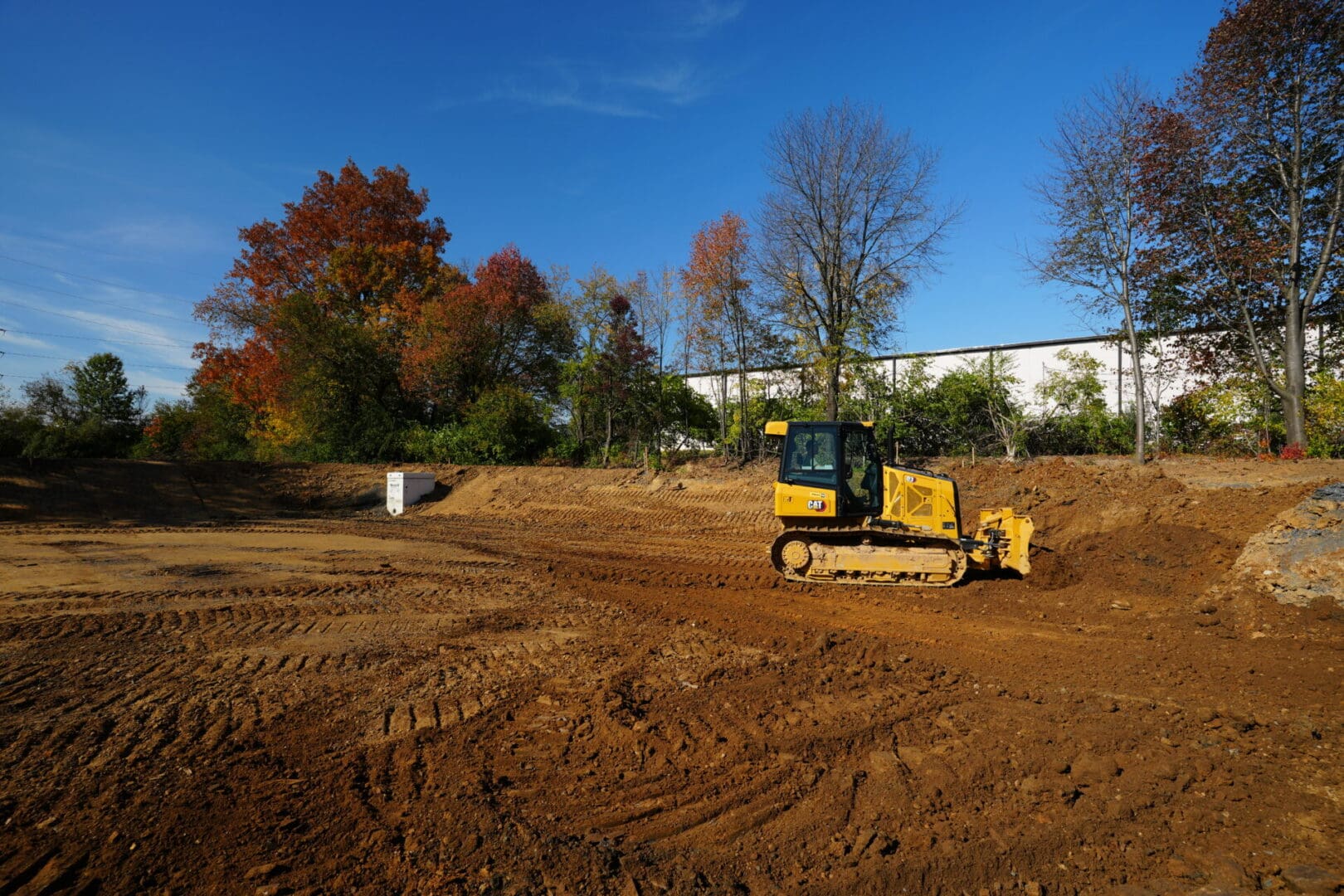 A bulldozer performing site work on a dirt field.