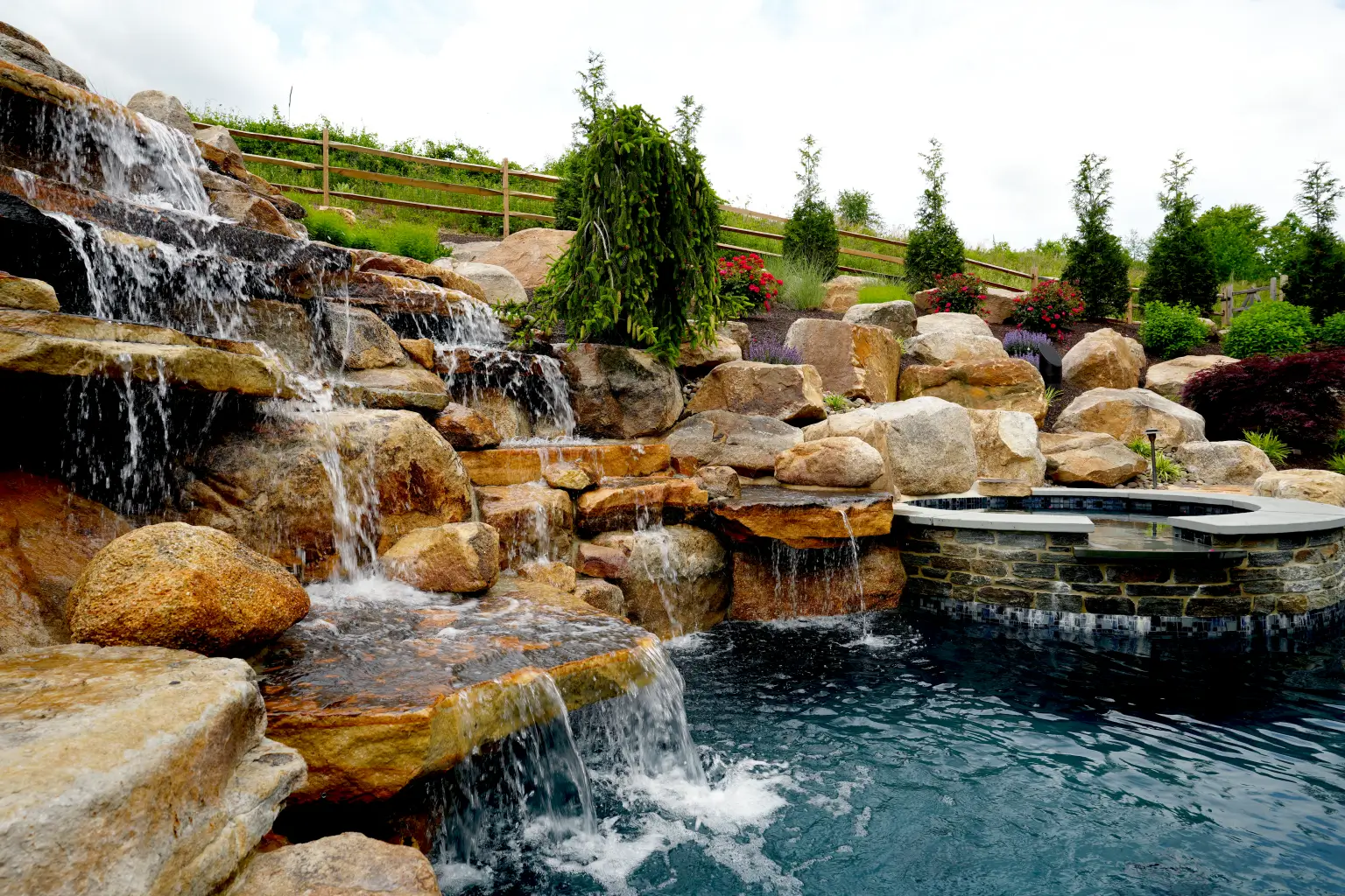 A stunning landscape design featuring a pool with a picturesque waterfall and rocks in the background.