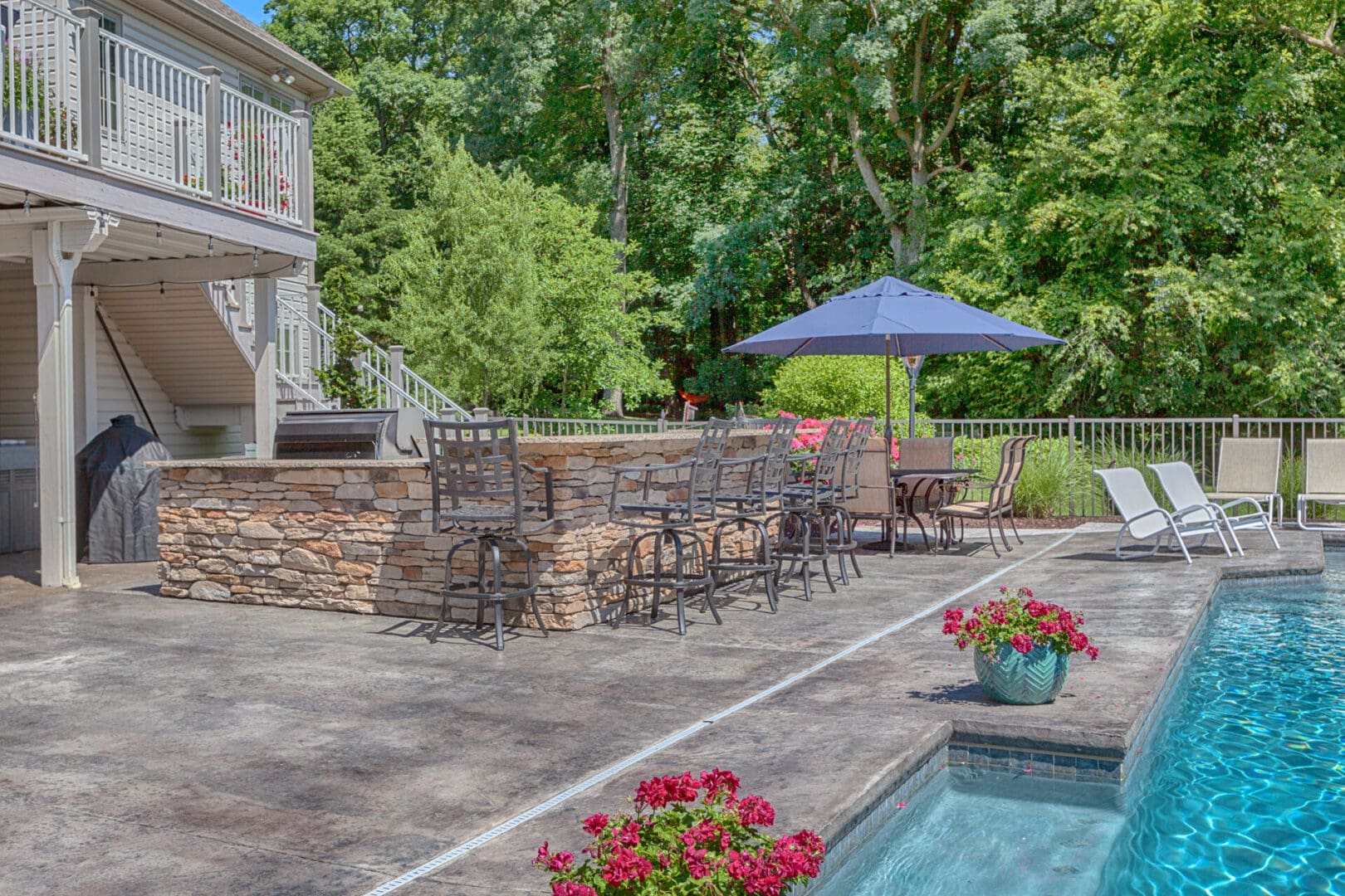 A backyard with a pool, custom outdoor kitchens, and patio furniture.