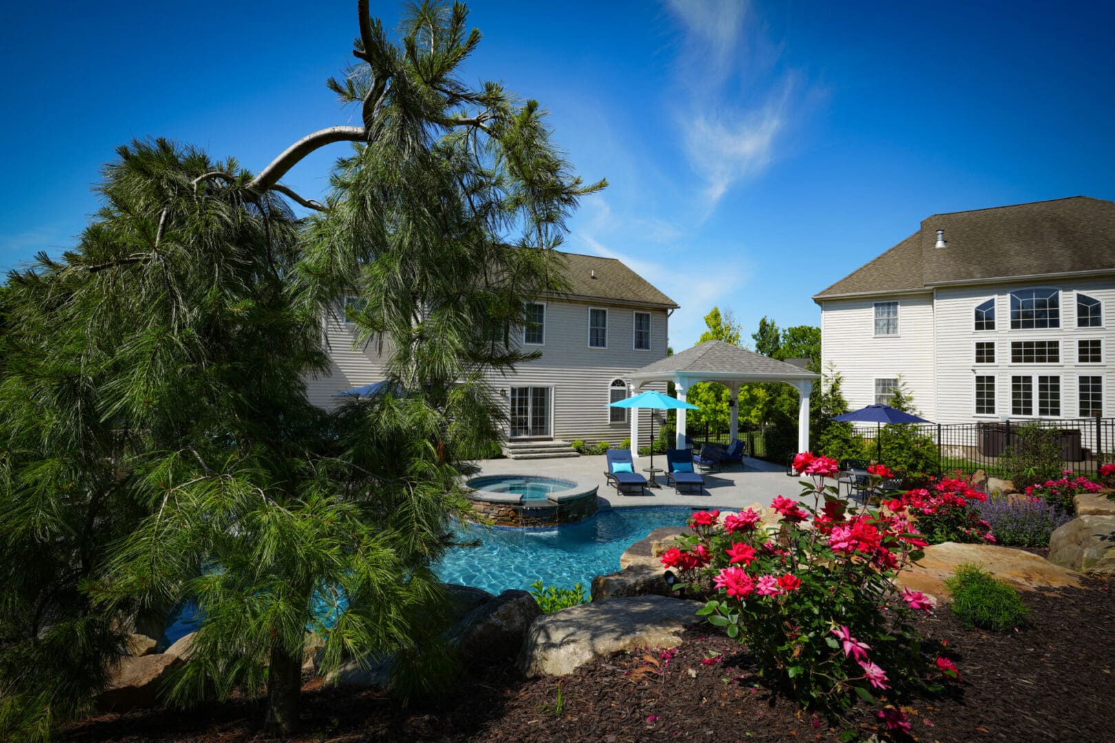 A backyard with a pool and flowers in the yard.