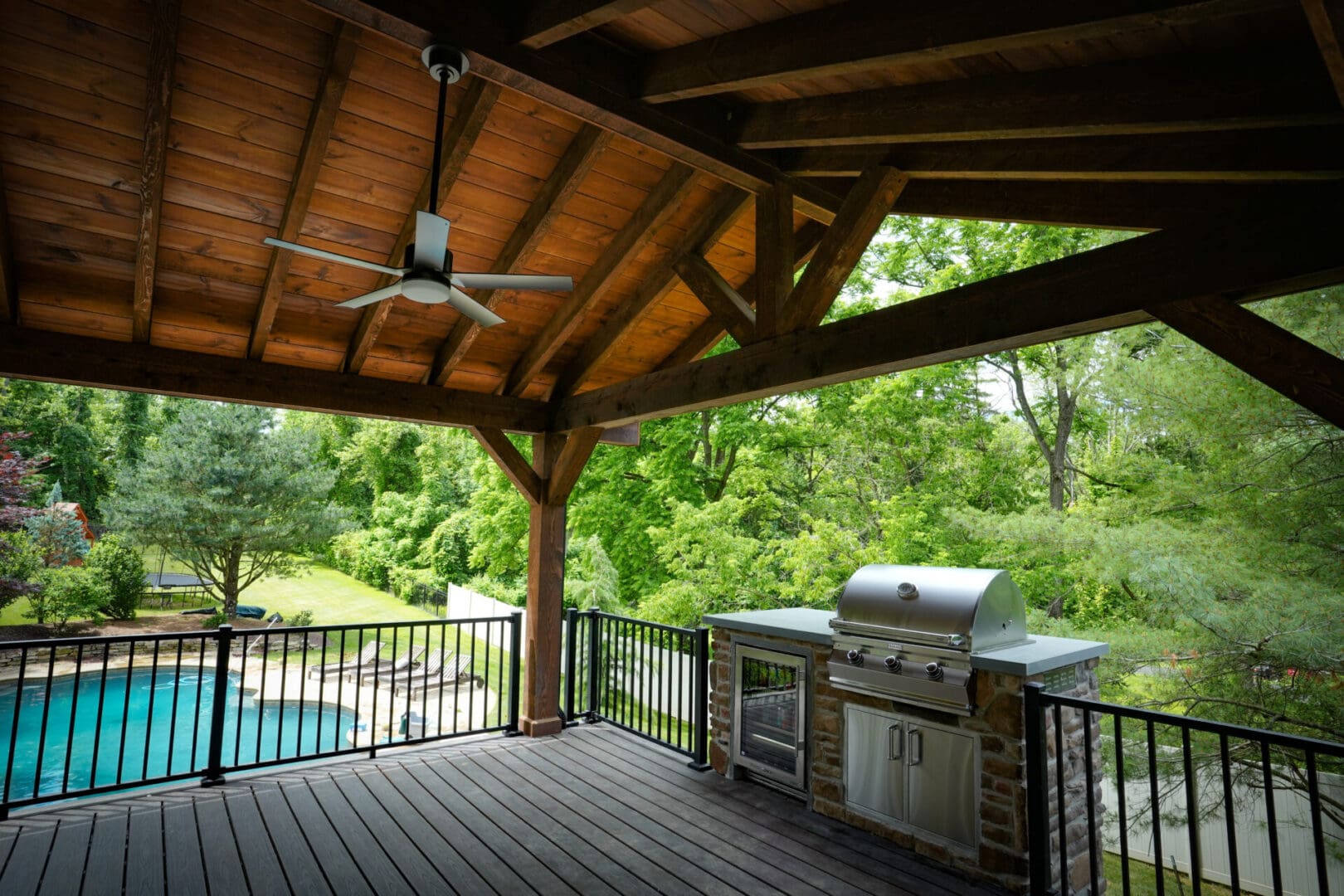 A covered patio with an outdoor grill and pool.