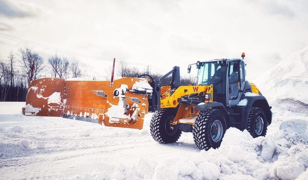 A yellow and black tractor is in the snow