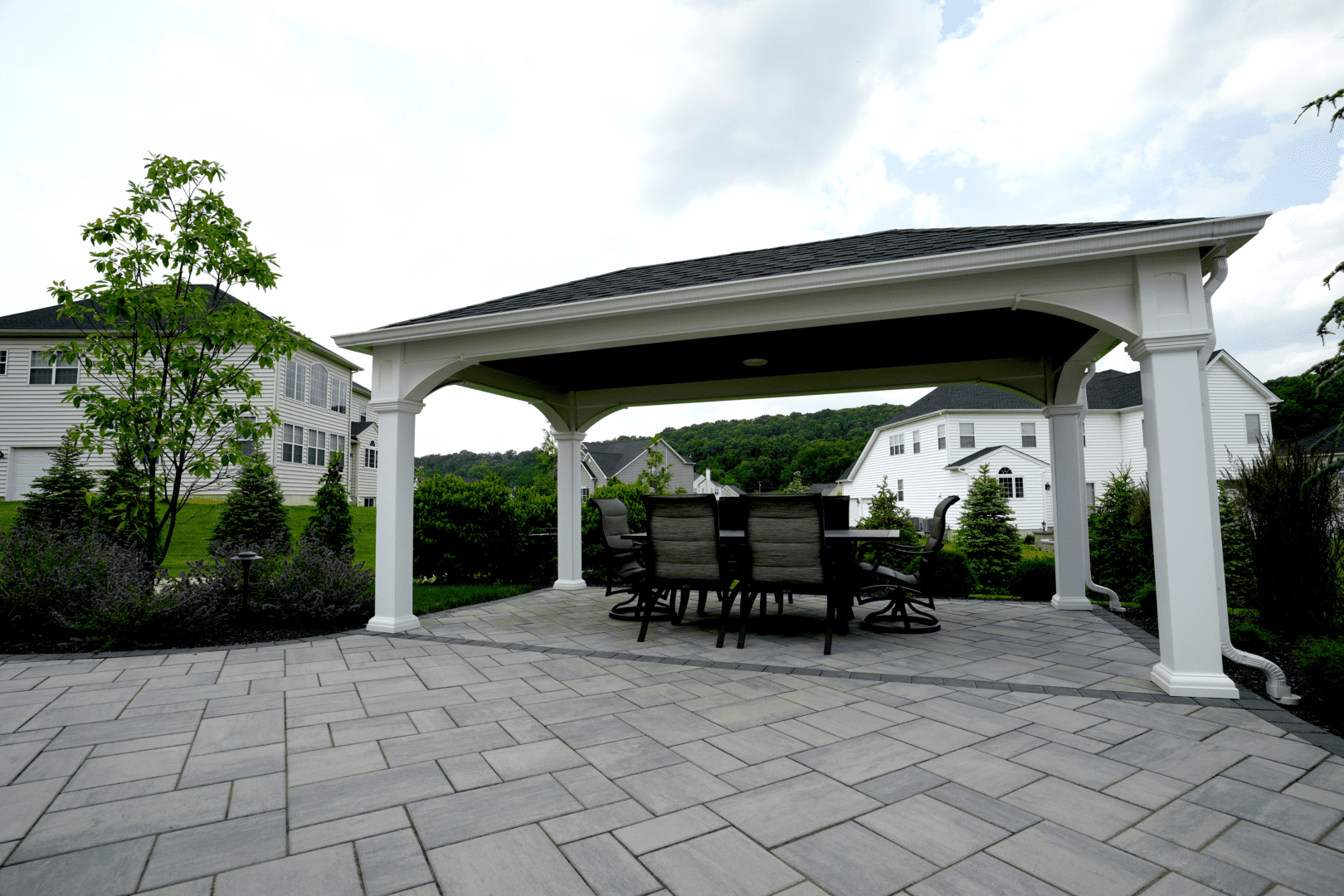 A patio with tables and chairs under an open pavilion.