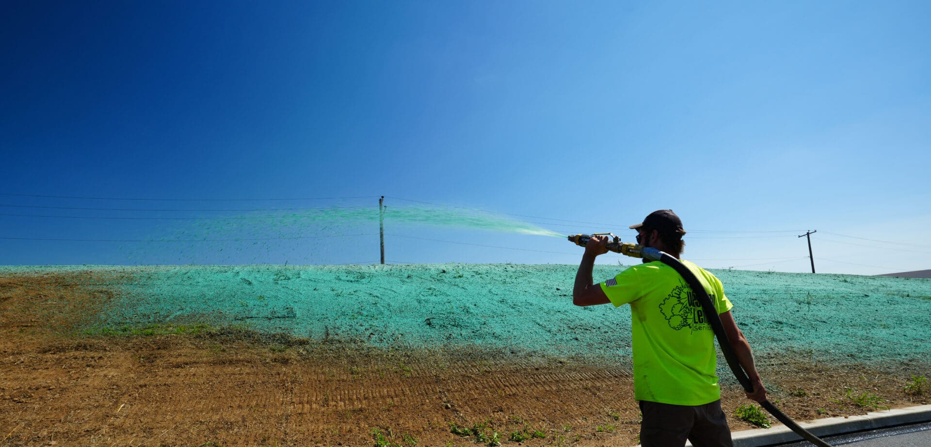 A man in a green shirt is spraying water from his mouth.