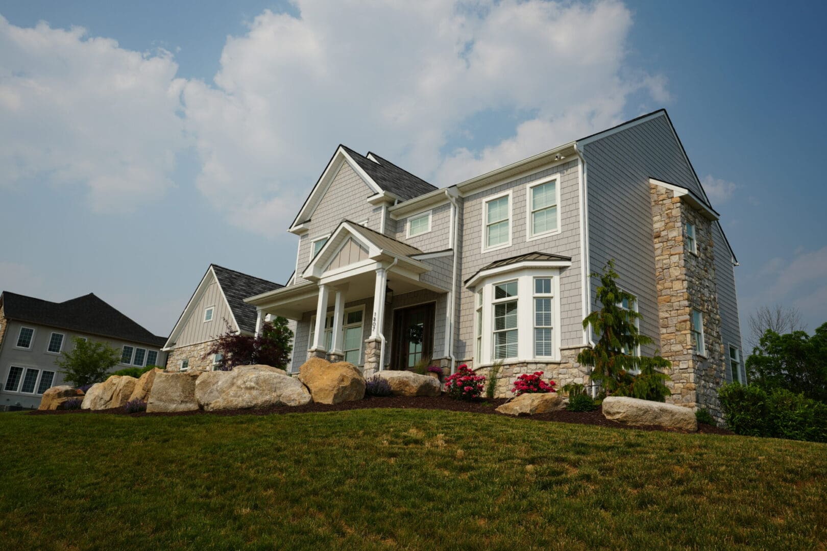 A large house with a big lawn and some rocks