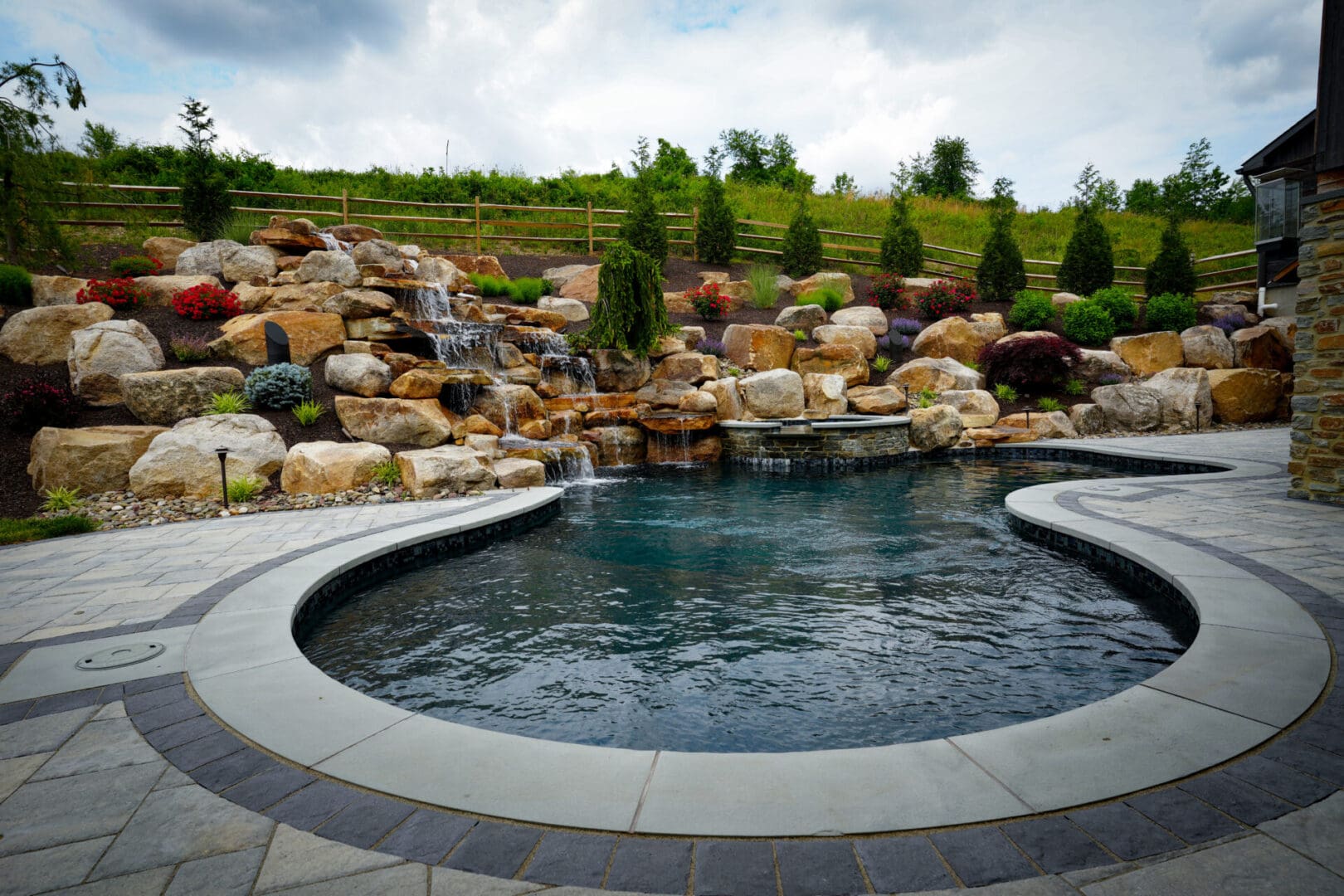 A pool with a waterfall and rocks in the background.