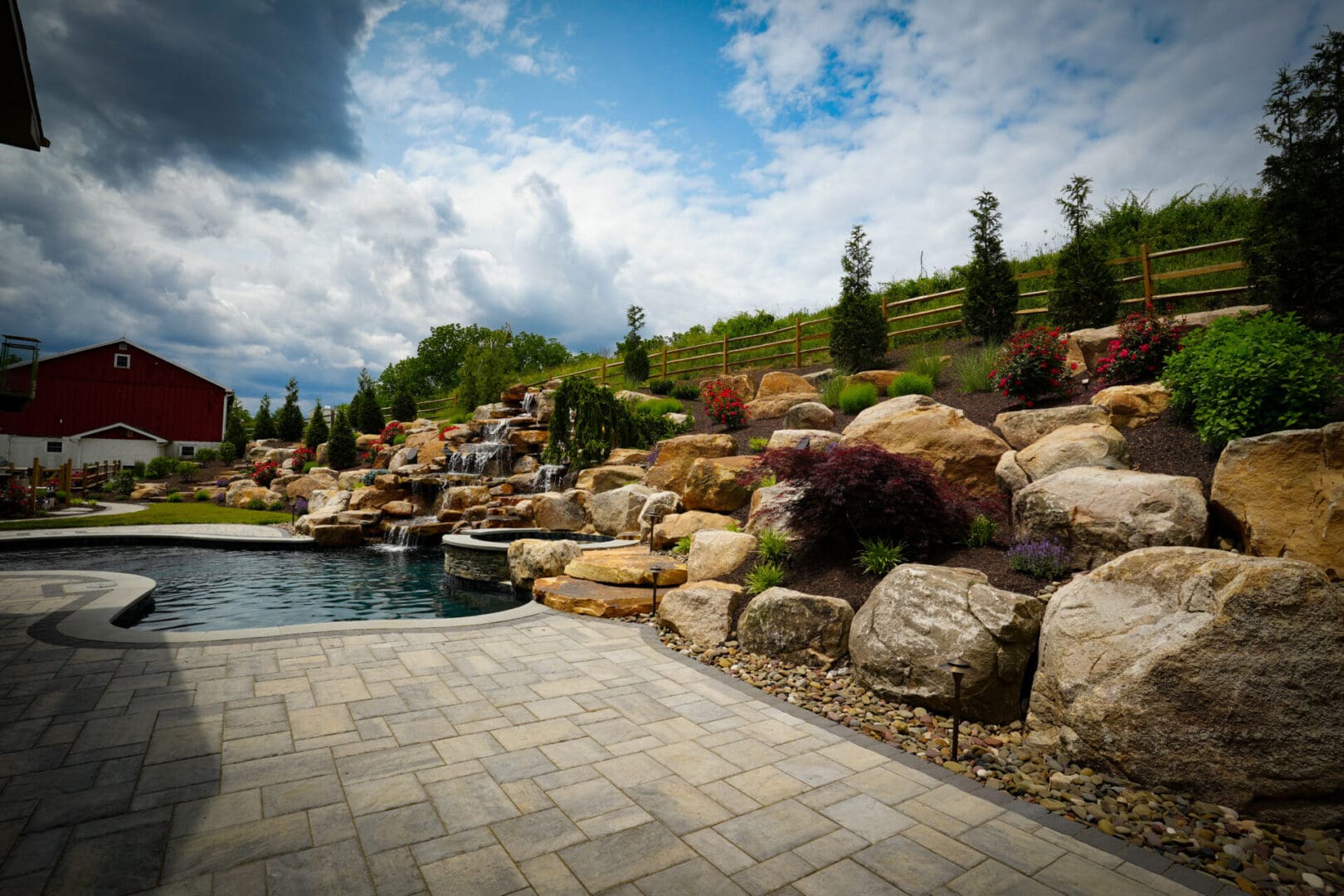 A pool with a rock wall and water feature.