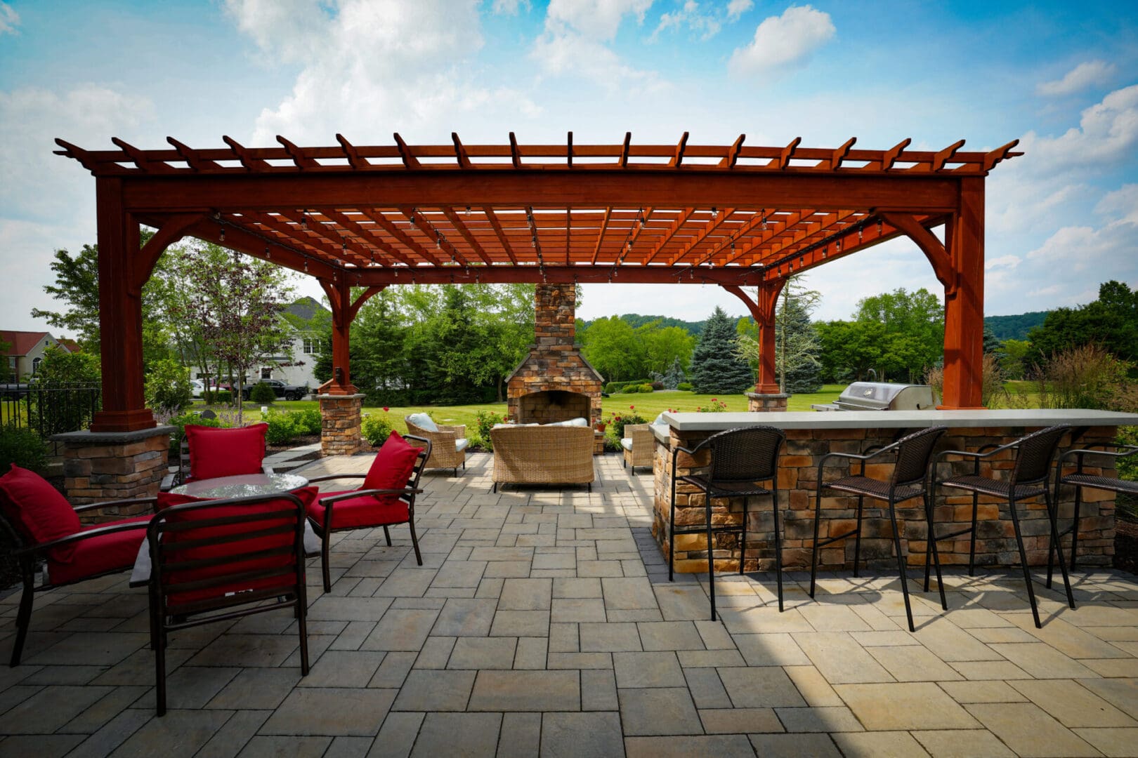 A patio with an outdoor fireplace and a pergola.