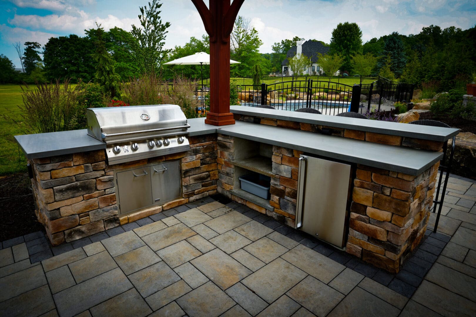 A grill and an outdoor kitchen with stone walls.