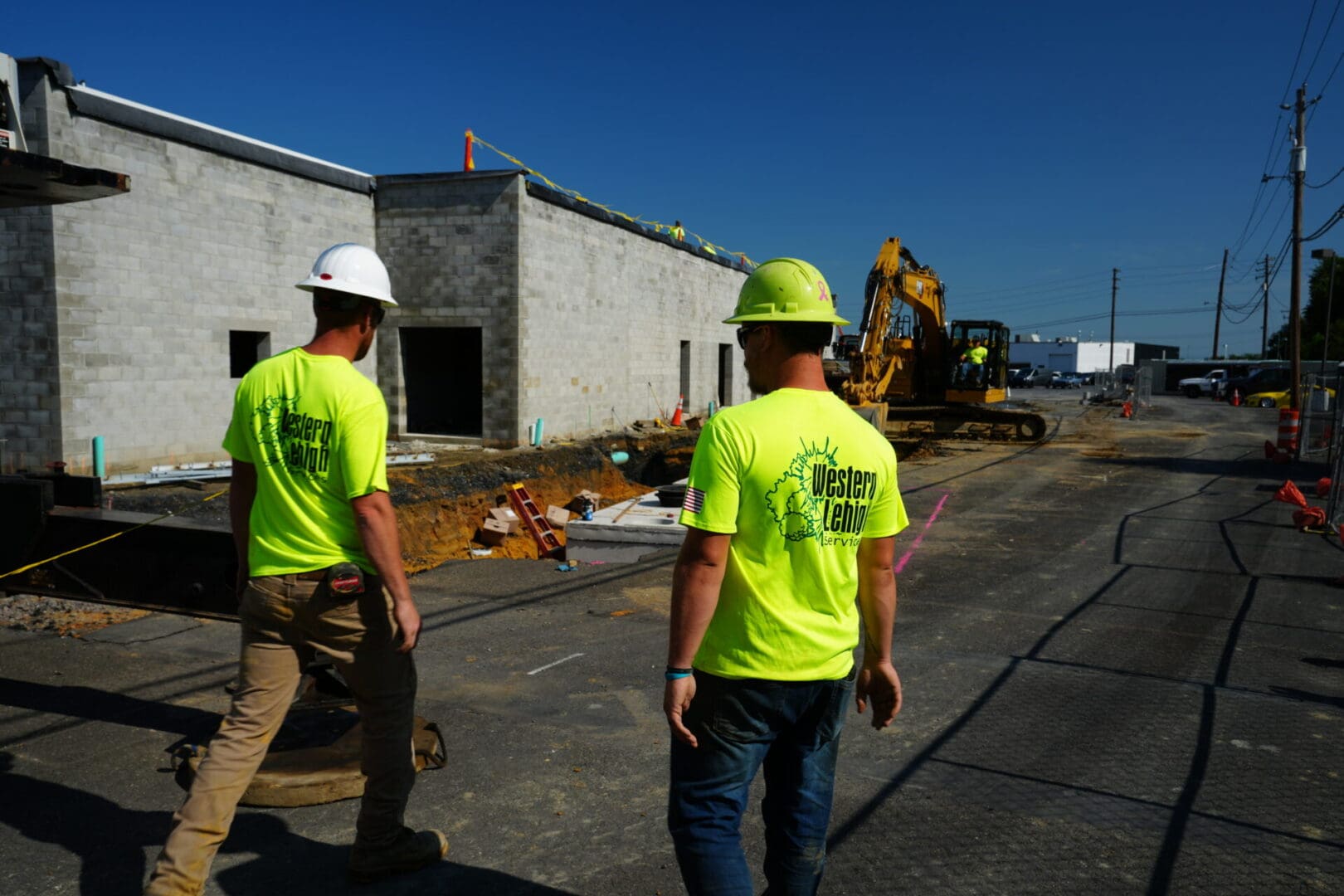 Two construction workers wearing neon shirts and hard hats.