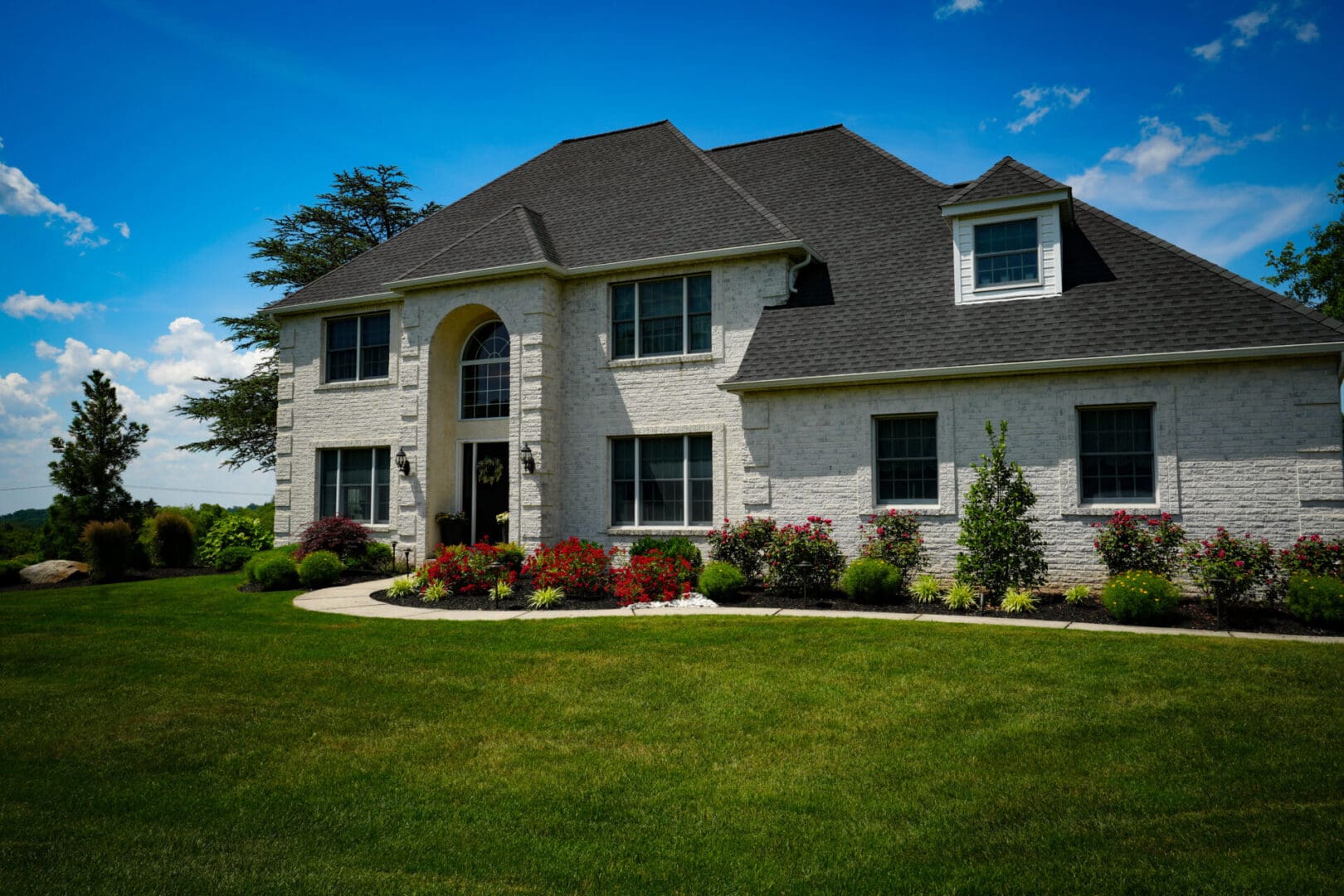 A large white house with a green lawn in front of it.