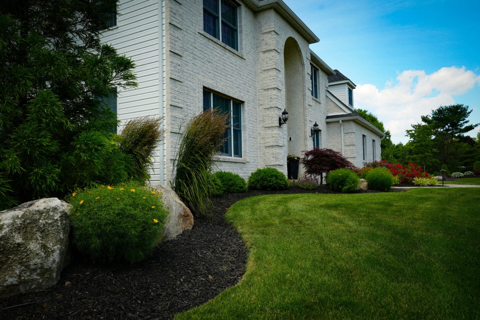 A house with bushes and trees in front of it.